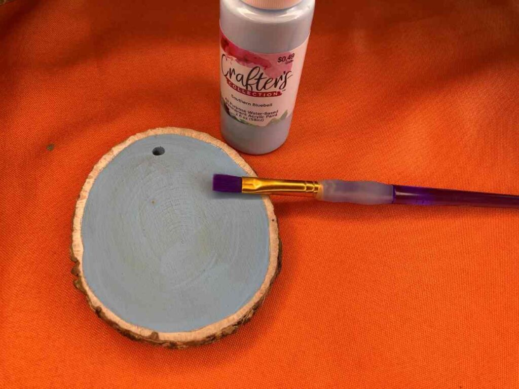 Use a paintbrush to add Mod Podge to your wood slice ornament before adding fabric