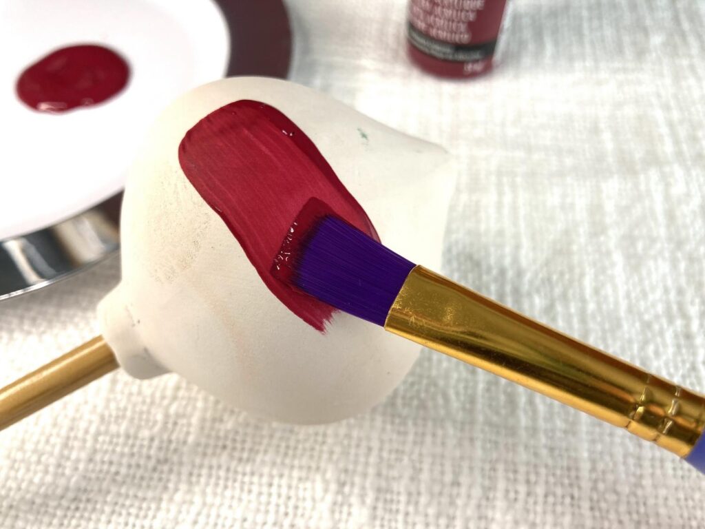 Applying a red base color on a wooden ornament