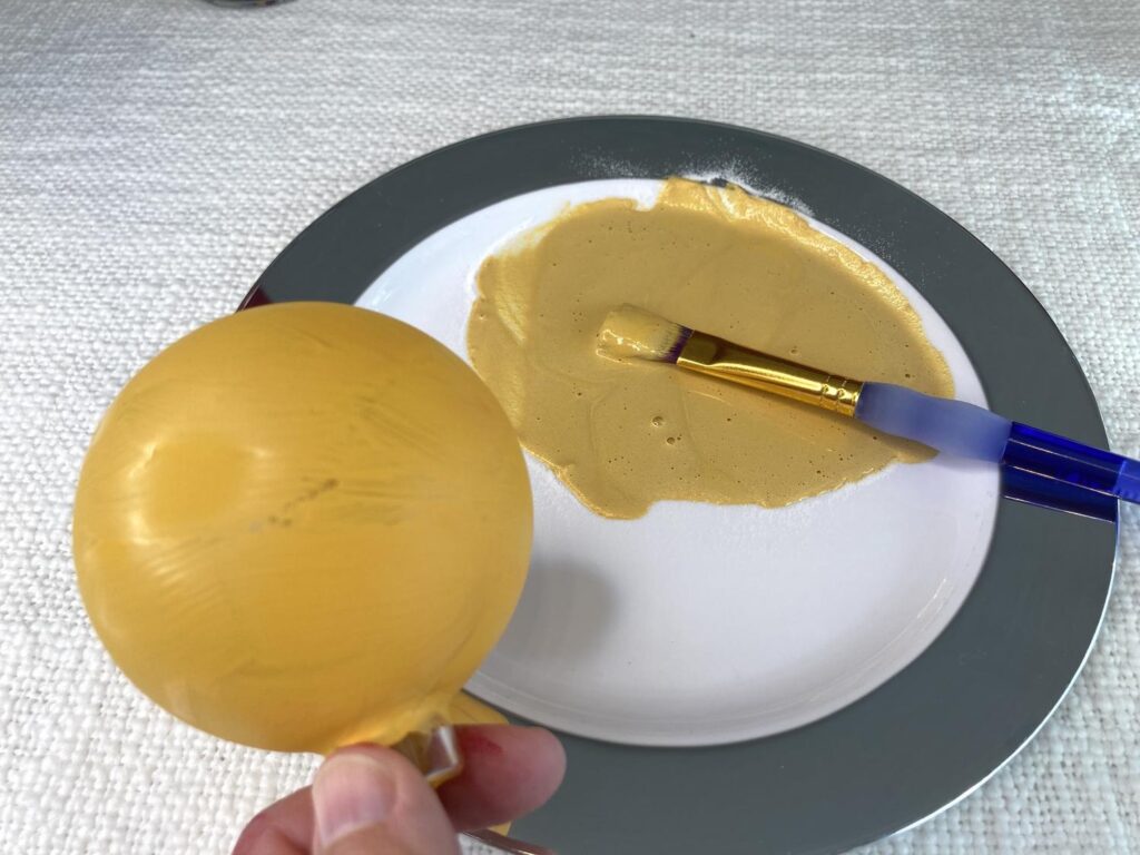 Wooden ornament painted with a base layer of yellow paint