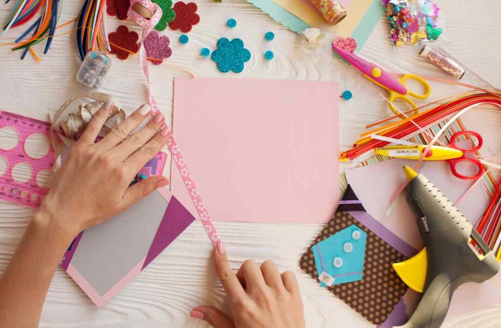 A woman's hands and a desk filled with supplies for how to start scrapbooking