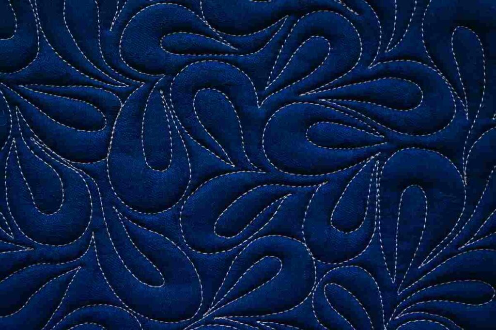 Close up of a blue quilt with intricate basting
