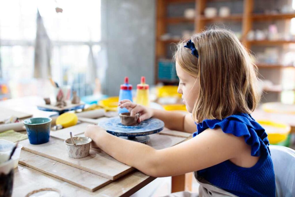 A young girl making a cup on a kids pottery wheel